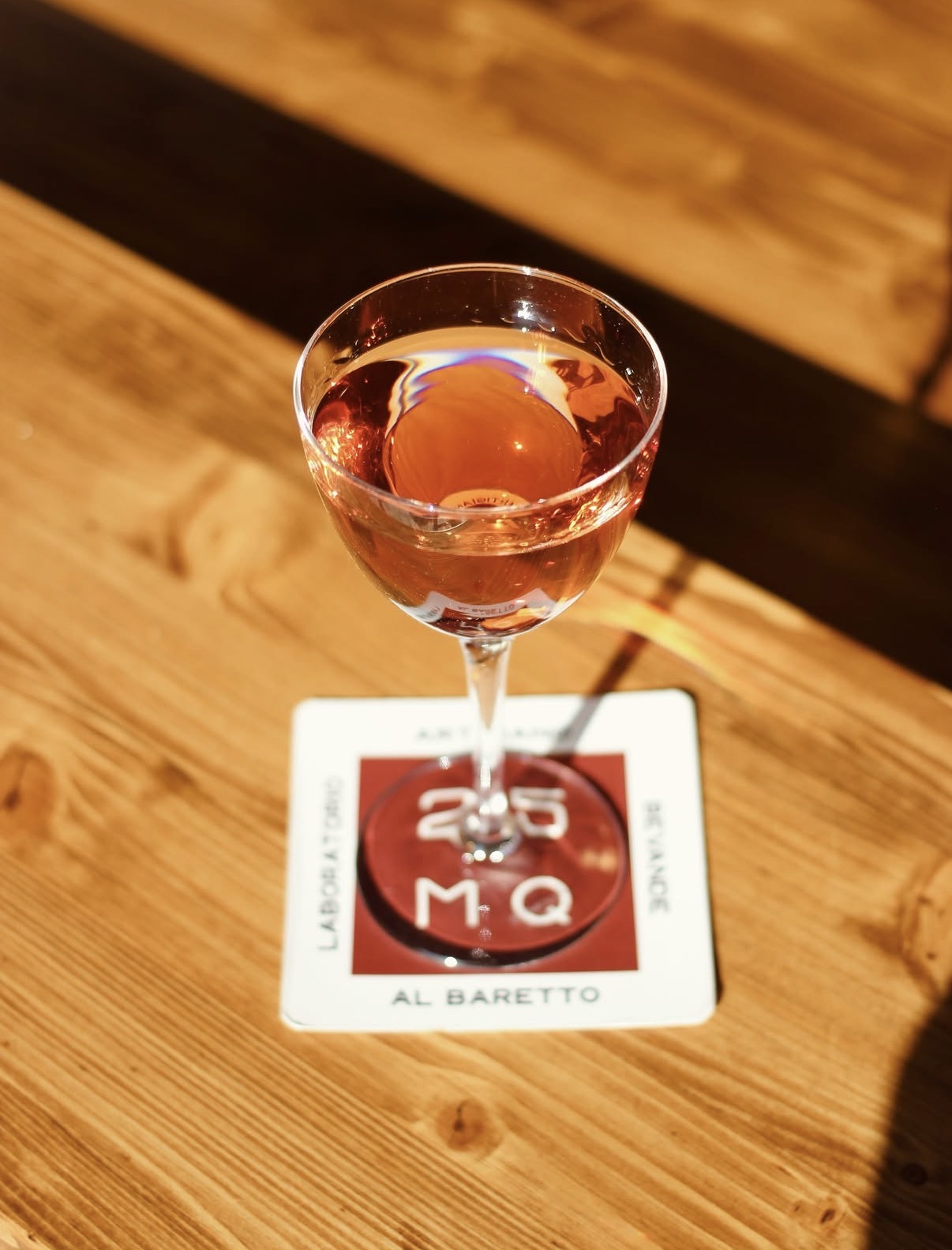 Cocktail rosato servito in coppetta sul sottobicchiere 25MQ